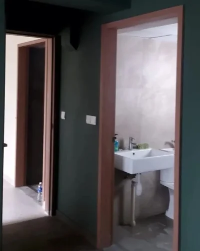 Dark green painted hallway walls with open doorways leading to a modern bathroom and an adjacent room.